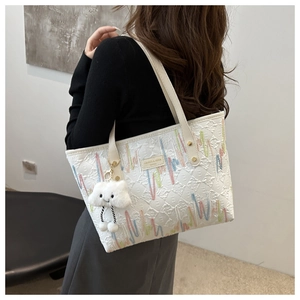 Detail of white striped tote bag with colorful wavy embroidery and plush cloud pendant