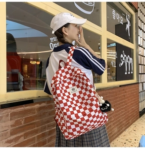 Side view of red and white checkerboard backpack with plush pendant and logo detail