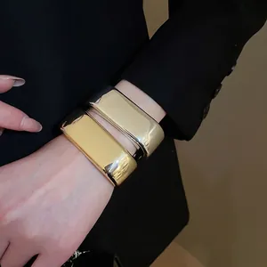 Minimalist wide wave cuff bracelets in gold and silver finish worn on wrist