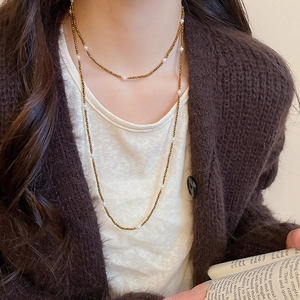 Double-layered beaded tiger eye sweater necklace styled on a model with a cozy brown sweater