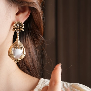 Boucles d'oreilles vintage dorées avec perles et strass portées par un mannequin