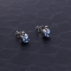 Dettaglio di orecchini in cristallo blu con base in metallo argento su pelle nera e passante