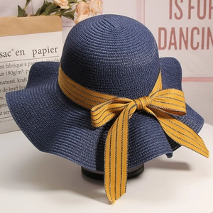 Close-up of a navy straw sun hat featuring a yellow striped ribbon bow for beach vacation