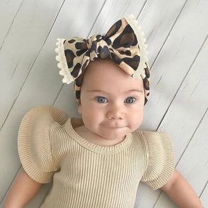 Close-up of soft baby headband featuring leopard print bow and cream fringe detail