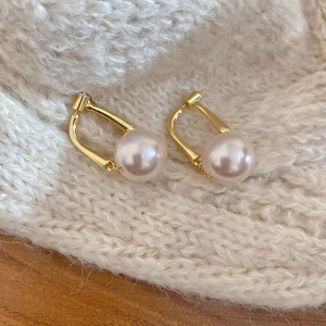Close-up of elegant round pearl earrings on a soft knit sweater background