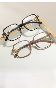 Detail view of large square frame glasses with gold metal hinges in black and brown