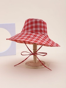Detail of red gingham sun hat with wide brim and matching chin strap ties on display stand