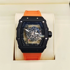 Detailed view of hollow skeleton dial watch with black tonneau case and orange rubber strap