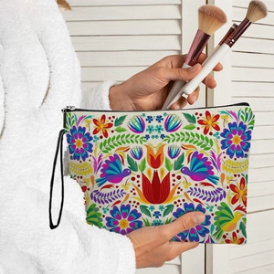 Large Mexican Otomi floral makeup bag with wrist strap held by model in soft lighting