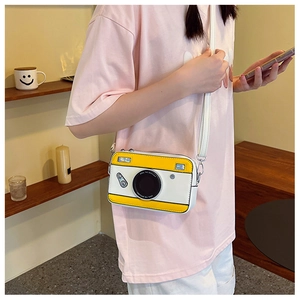 Detail of camera-shaped crossbody bag in yellow and white PU leather with adjustable strap