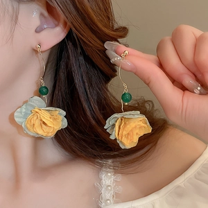 Detail showing long yellow fabric flower earrings with green resin beads on gold hooks