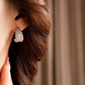 Détail de boucles d'oreilles argentées en forme de C avec texture portées par un mannequin