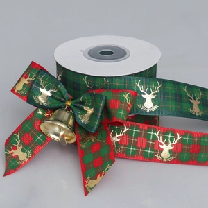 Detail of Christmas ribbon with gold elk print, red plaid bow and a metallic gold bell