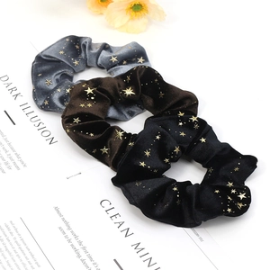 Close-up of velvet scrunchies with gold star prints in blue, brown and black colors