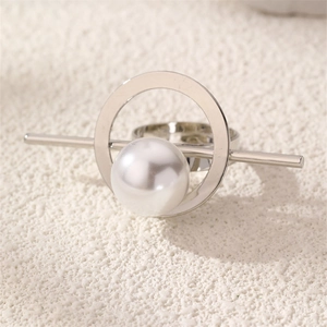 Detailed close-up of a silver geometric open ring featuring a large white pearl center