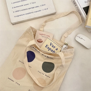 Detailed shot of beige canvas tote with artistic colour palette print on a desk