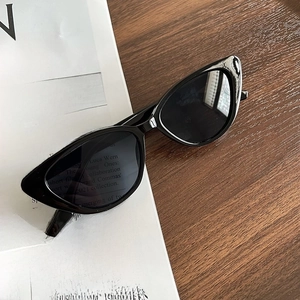 Close-up of black cat-eye sunglasses on a wooden table with vintage newspaper