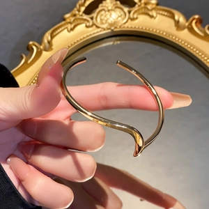 Detail shot of wavy gold-plated cuff bracelet featuring a minimalist irregular design