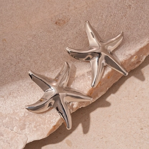 Macro shot of polished silver starfish pendants on a textured stone surface