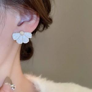 Gros plan d'élégantes boucles d'oreilles fleurs blanches portées par un mannequin au style épuré