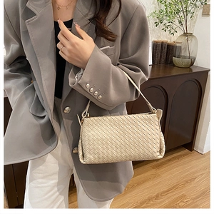 Elegante borsa a tracolla beige intrecciata abbinata a un blazer grigio per un look moderno