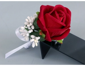 Detail of a red velvet artificial rose boutonniere with white berries and satin ribbon
