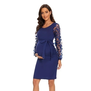 Dettaglio dell'abito premaman con maniche in pizzo blu scuro e nastro decorativo in vita