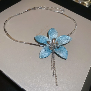 Macro detail of blue flower pendant with silver tassels and sleek snake chain necklace