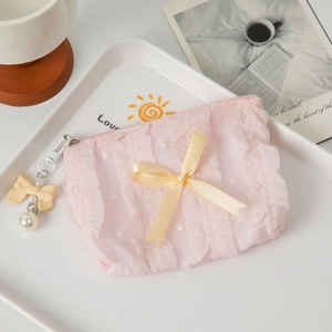 Detailed shot of pink ruffle makeup bag with yellow ribbon bow and pearl charm