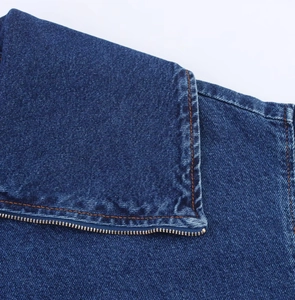 Dettaglio giacca di jeans blu scuro con cuciture arancioni e cerniera in metallo