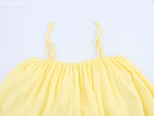 Détails des fines bretelles et de l'encolure plissée sur la robe en mousseline jaune