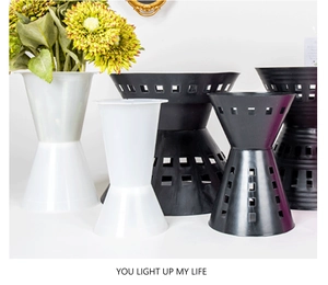 Detail of modern hourglass plastic flower vases in black and white with geometric holes