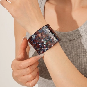 Detailed close-up of a wide marble pattern acetate cuff bracelet on a model's wrist