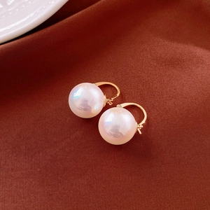 Détail macro d'élégantes boucles d'oreilles créoles dorées avec perles blanches brillantes