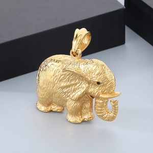 Macro view of a gold-plated elephant pendant with intricate skin texture and black eyes