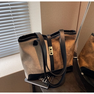 Close-up of color-block canvas tote bag with leather trim and gold metal buckle detail