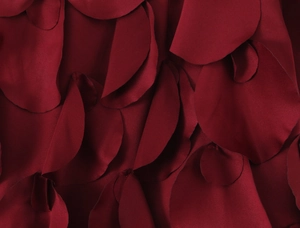 Vue macro de pétales de tissu en satin bordeaux superposés montrant une texture lustrée