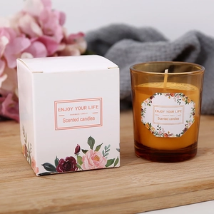 Handmade soy wax candle in brown glass jar with gift box on a wooden table