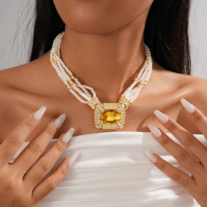 Detail of layered pearl necklace featuring a large square yellow gemstone pendant