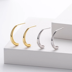 Detailed view of silver and gold C-shaped petal stud earrings on a geometric stand