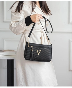 Detailed shot of a black women shoulder bag with gold V logo and tassel charm for daily wear.