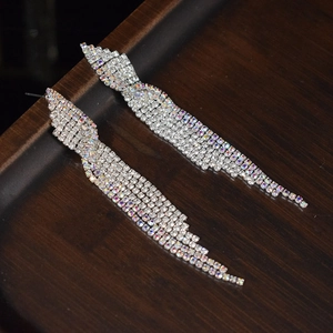 Sparkling long rhinestone tassel earrings for brides and parties on dark wood tray