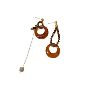 Asymmetrical resin tiger eye earrings with brown hoops and gold chains on white base
