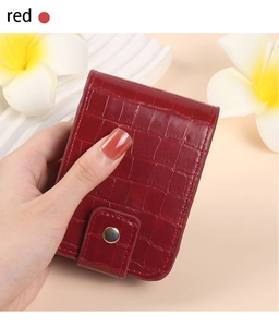 Detail of red croc-embossed lipstick pouch with gold snap button and built-in mirror