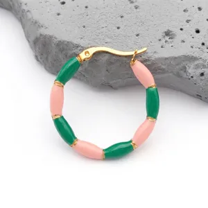 Close-up of bamboo-style earrings with pink and green enamel on golden stainless steel