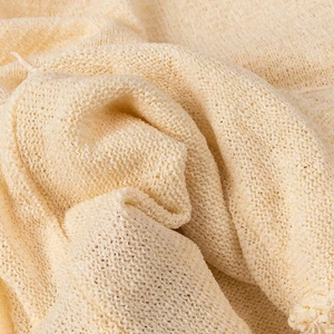 Vista macro del tessuto a maglia beige che mostra la trama intrecciata e l'alta qualità