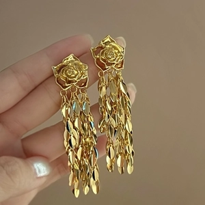 Gros plan détaillé de boucles d'oreilles rose dorée avec de longs glands en métal