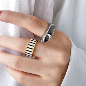 Detail of colorful checkerboard enamel ring and polished silver geometric band on finger