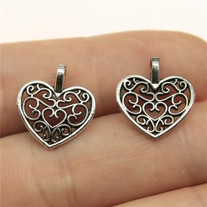 Silver hollow heart-shaped alloy pendant charms on a fingertip for size reference