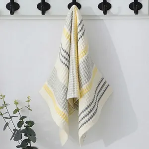 Detail of waffle weave cotton towel with yellow and grey stripes hanging on a hook